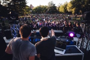 A DJ playing music to a party crowd in a park